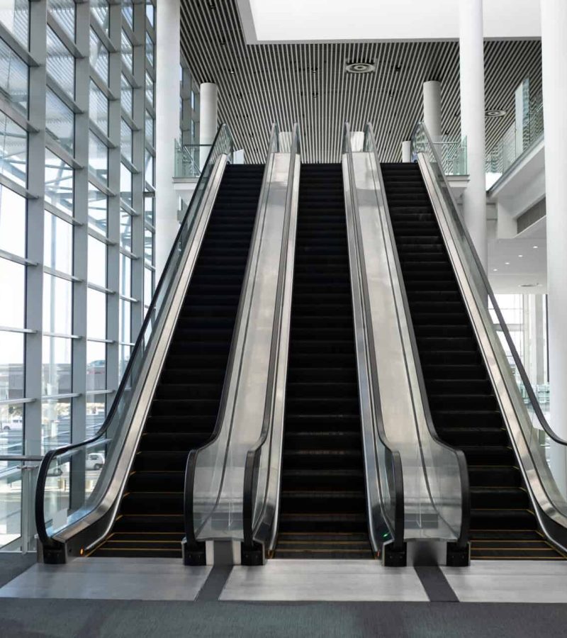 Front view of three modern escalators in a office lobby against inside buildings in background